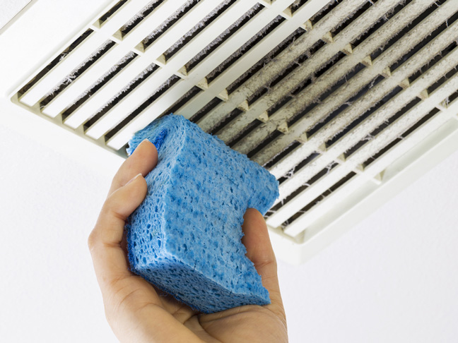 hand cleaning a vent with a blue sponge